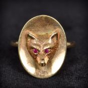 A 9 ct gold and ruby ring Of oval form, centred with a fox mask with ruby inset eyes. 2 cm high.