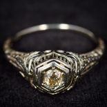 An 18K white gold diamond solitare ring With scroll pierced shoulders and a stop engraved shank,