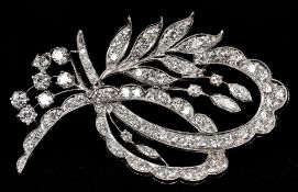A diamond set platinum spray brooch Of entwined floral form. 5 cm long.