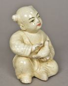 A Chinse Song style porcelain figure of a child holding a bird With allover creamy glaze. 15.