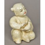 A Chinse Song style porcelain figure of a child holding a bird With allover creamy glaze. 15.