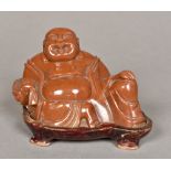 A Chinese carved hardstone Buddha Modelled recumbent on a wooden plinth base. 9 cm high overall.