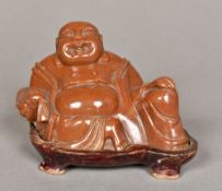 A Chinese carved hardstone Buddha Modelled recumbent on a wooden plinth base. 9 cm high overall.