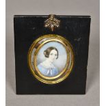 A framed miniature portrait on ivory Depicting a young girl wearing a pink collared blue dress,