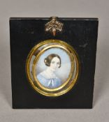 A framed miniature portrait on ivory Depicting a young girl wearing a pink collared blue dress,