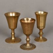 Three 18th/19th century gunmetal wager cups Each of typical flared form with a turned knop and