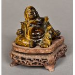 A Chinese carved tiger's eye Buddha Modelled recumbent on carved wood plinth base.