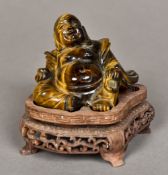 A Chinese carved tiger's eye Buddha Modelled recumbent on carved wood plinth base.