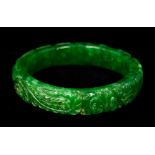 A Chinese apple green jade bangle Decorated with a phoenix and a dragon amongst scroll work. 7.