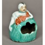 A Chinese porcelain brush washer Modelled as a young boy holding a fish, climbing a boulder.