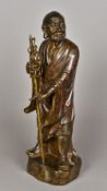 A Chinese cast bronze figure of a Lohan Modelled standing in decorated robes holding a staff,