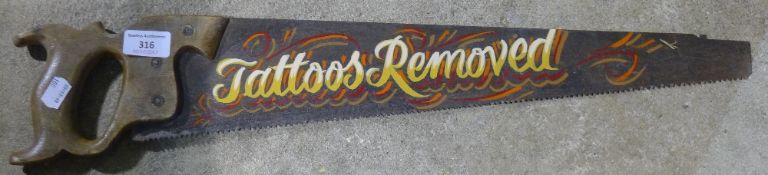 A painted saw inscribed ''Tattoos Removed''