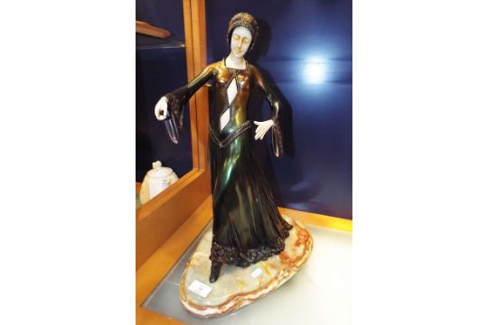 An Art Deco style figure of a female dancer raised on a stepped onyx base hands