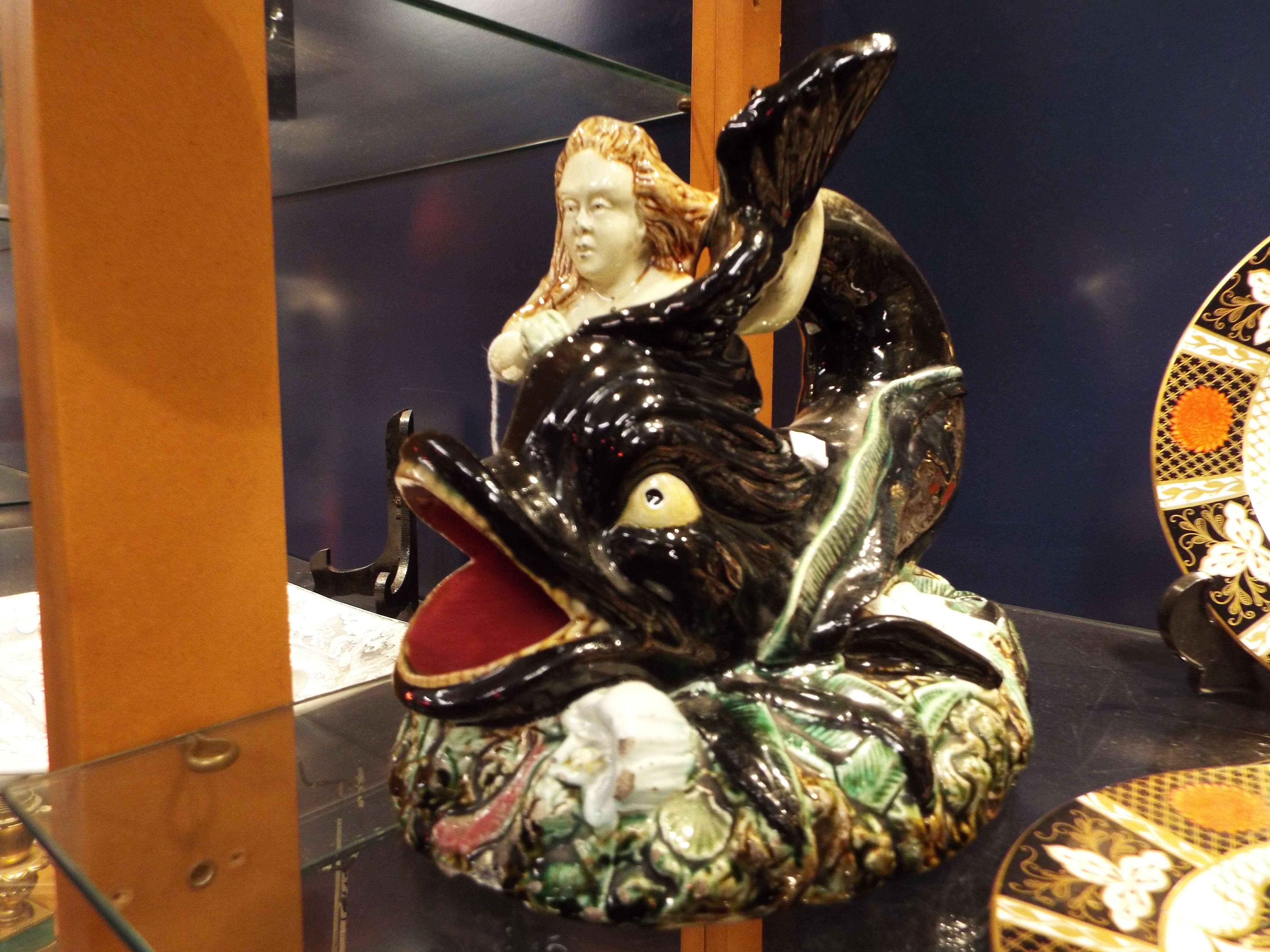 A Continental Majolica figurine of 'Arion' the merman with dolphin resting on a rock formation