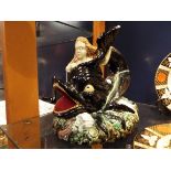 A Continental Majolica figurine of 'Arion' the merman with dolphin resting on a rock formation