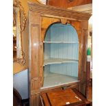 An antique pine corner cabinet having two shaped shelves above a double cupboard