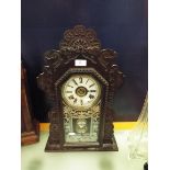 An early 20thC gingerbread clock with decorated glass panel,