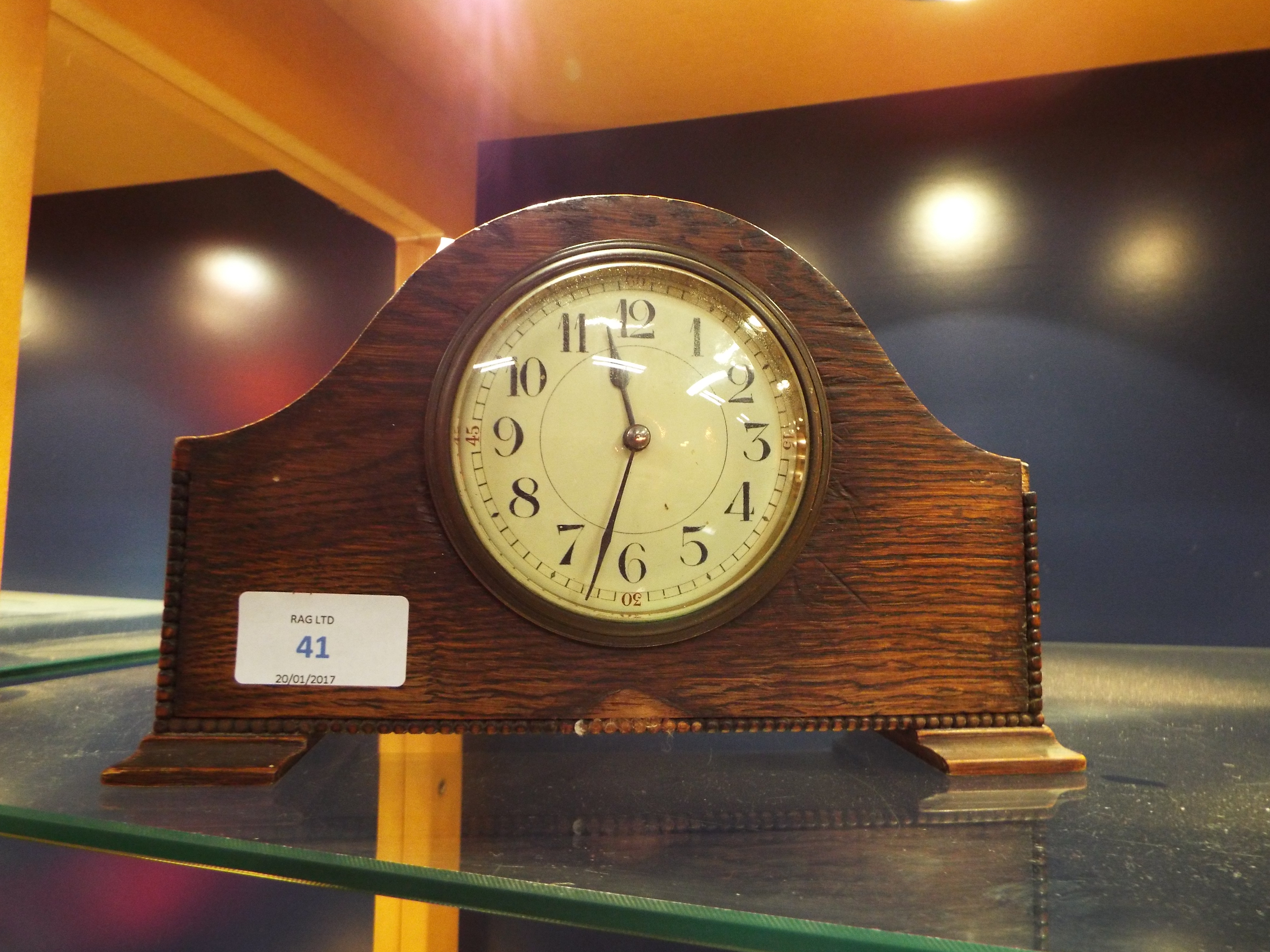 An early 20thC oak dome top mantel clock the enamel dial with Arabic numerals,