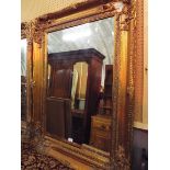 A large bevel edged mirror with floral decorated gilt gesso frame
