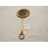 A heavy gilt metal circular hand mirror with stylised border and ring handle