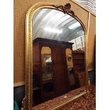 A large 20thC oval mantle mirror the gadrooned gilt frame with applied floral scrolls surmounted