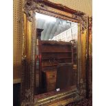 A large bevel edged mirror with floral decorated gilt gesso frame