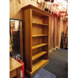 A large light oak bookcase fitted with four adjustable shelves and flanked by fluted pilasters