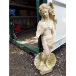 A reconstituted stone garden ornament in the form of a nude female standing in a clam shell