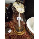 A baluster shaped glass hurricane lamp raised on an ornate gilt base
