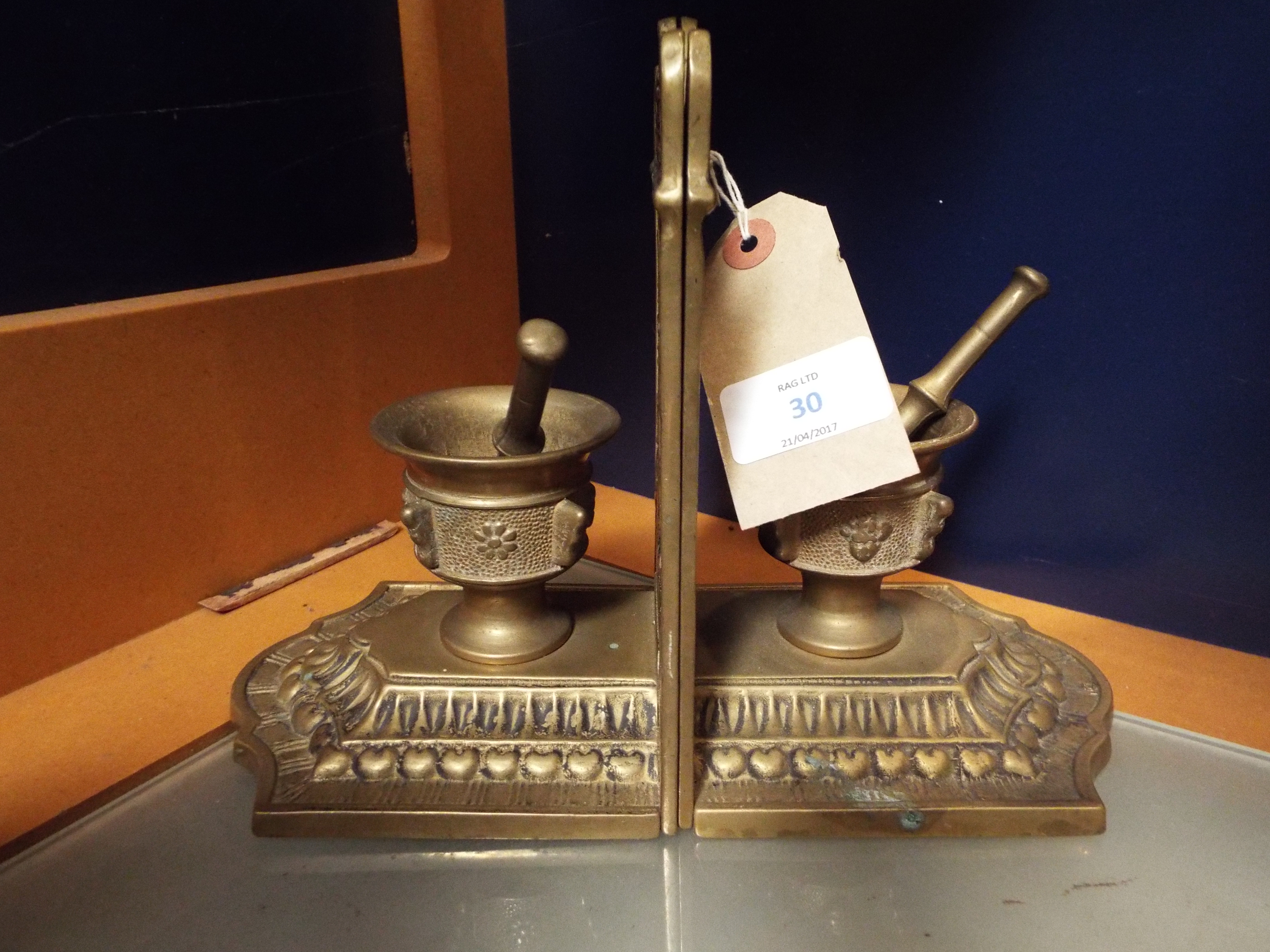 A pair of ornate brass bookends in the form of pestle and mortar