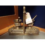A pair of ornate brass bookends in the form of pestle and mortar