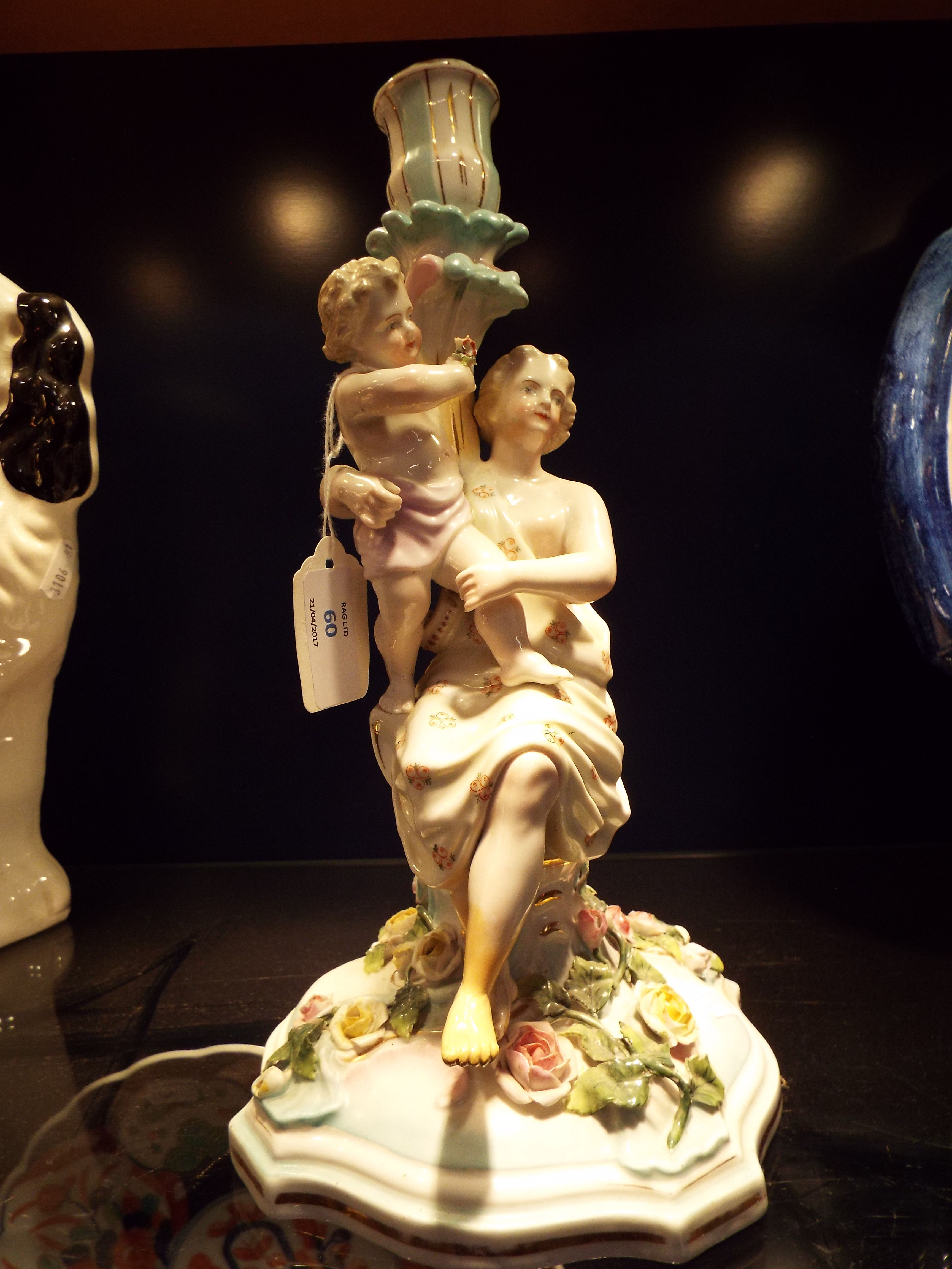 A 19thC continental Meissen style figurative candlestick depicting a classical female with putti