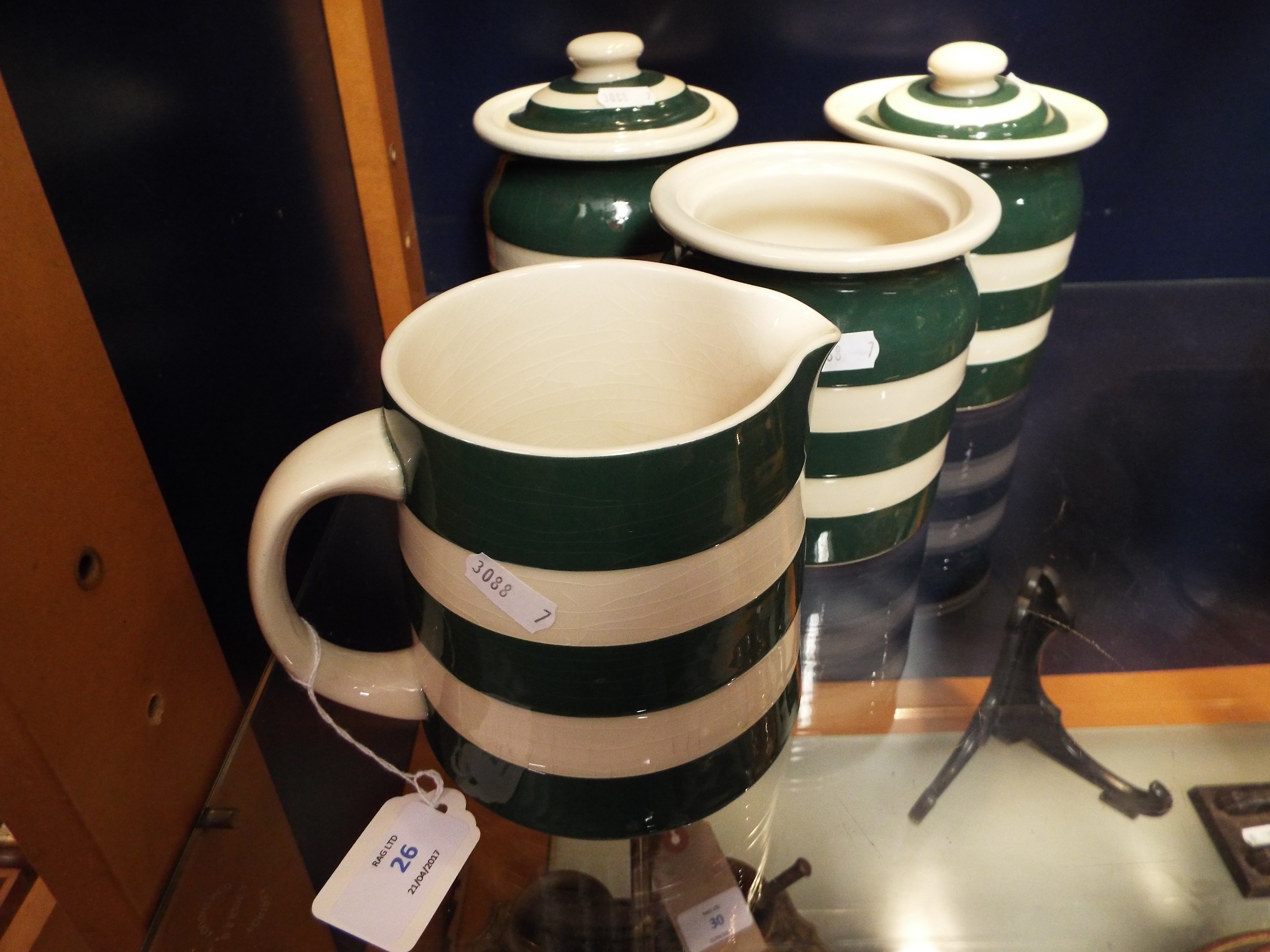 A set of three green and white kitchen storage jars together with a similar jug (one lid missing)