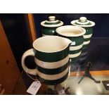 A set of three green and white kitchen storage jars together with a similar jug (one lid missing)