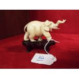 A carved ivory elephant resting on a wooden base Trunk has bee off and re-glued and