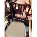 An Edwardian inlaid mahogany open arm chair with spindle back and serpentine seat raised on square