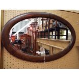 A 1930's oval oak framed mirror with bevel edge plate