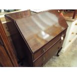 A walnut bureau the fall front enclosing inner compartments with three drawers under