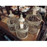 A pair of ornate cream painted wire-work bird cages