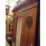 An Art Nouveau satin wood wardrobe the central door with drape flanked by two poker work and carved