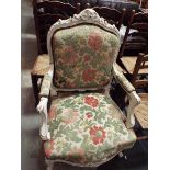 A French white painted regency style arm chair with floral carved top rail over a padded back and