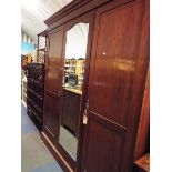 An Edwardian mahogany and boxwood strung triple wardrobe having central mirror door