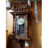 An early 20thC walnut cased architectural style wall clock with enamel dial and Roman numerals