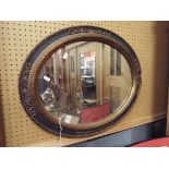 An oval wall mirror having painted ornate frame