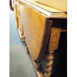 A mid 20thC light oak oval gate leg table raised on barley twist supports