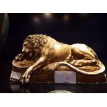 A gilt porcelain figure of a recumbent lion resting on a stylised rocky base,