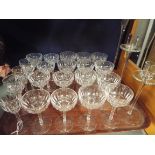 A part suite of facet cut wine and sherry glasses together with three graduated candlesticks