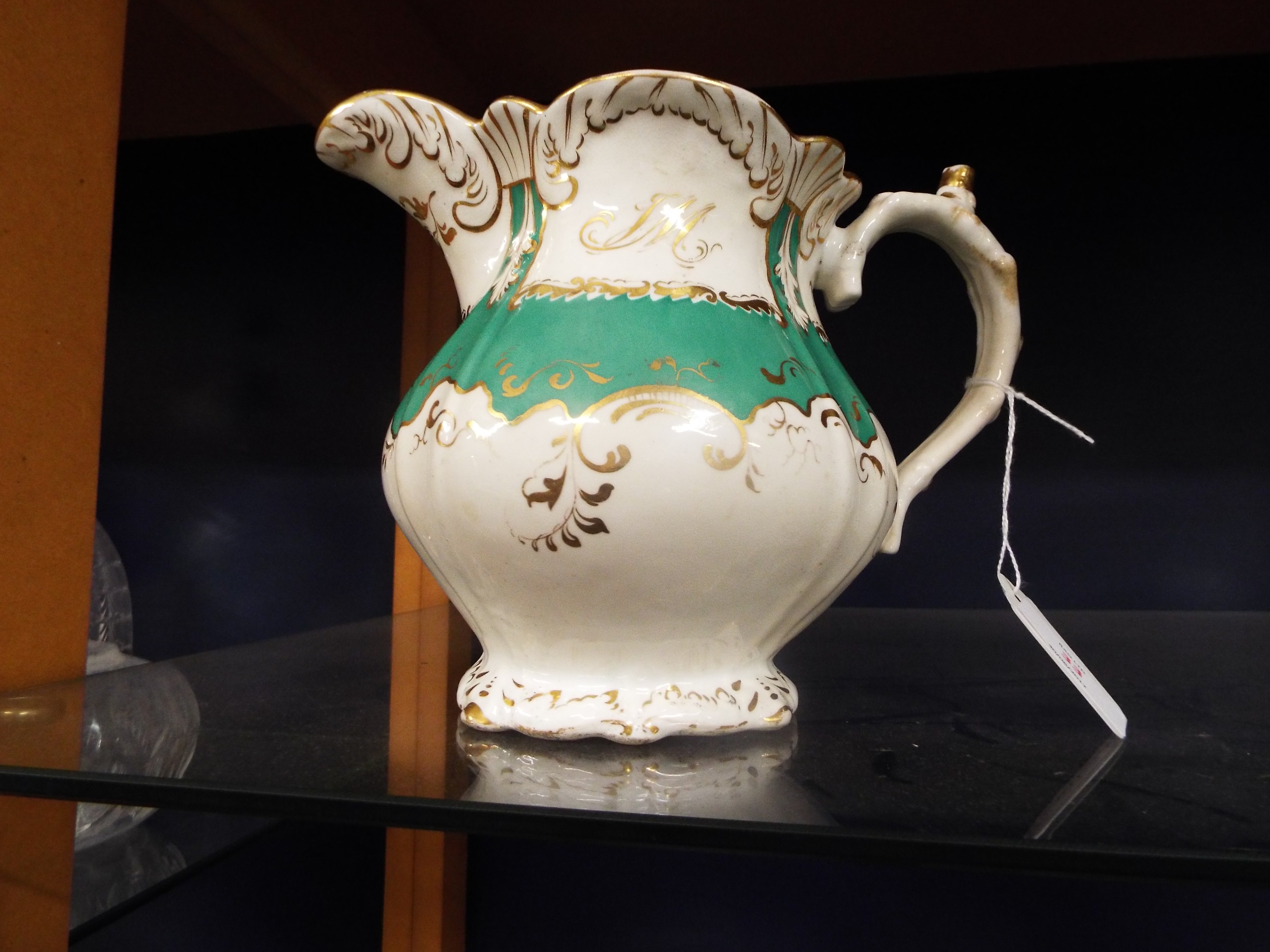 A 19thC Rockingham porcelain jug with green and gilt scrolling decoration and initialled to the