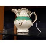 A 19thC Rockingham porcelain jug with green and gilt scrolling decoration and initialled to the