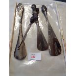 Three silver handled shoe horns and a similar button hook,